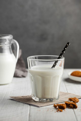  Glass of milk with a straw, cookies on gray background. The concept of milk, dairy products, farm products. Copy space.