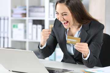 Excited executive paying with card on laptop at office