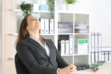 Executive woman breathing fresh air sitting at office