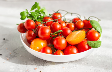 Red cherry and yellow tomatoes with baby spinach on the white plate. Healthy food, vegan or diet nutrition concept.