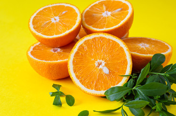 Creative summer background made half of oranges with leaves on yellow paper background.