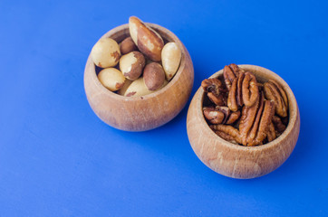 Pekan and brazil nuts on blue background. Healthy food