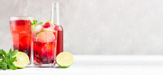 Lemonade or non-alcohol cocktail with raspberry, lime and mint in glass on grey background. Summer berry drink.