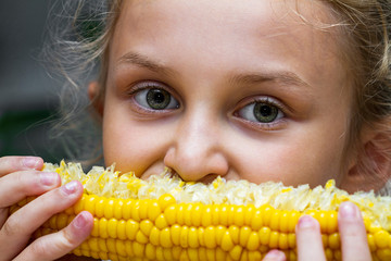 Naklejka premium Young girl eating a boiled corn. Close-up, selective focus