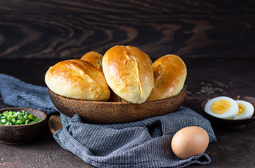 Fresh baked patties with egg and green onion stuffing. Dark brown stone table. Traditional Russian and Ukrainian homemade savory pirozhki. Rustic style.