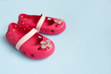 Baby pink rubber summer shoes on blue background with copy space