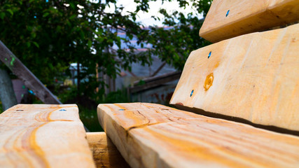Side view of a handmade wooden bench. Garden furniture. Untreated wood. Rest in the country. Landscaping. Selective focus.
