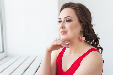 Close-up of fashion shoot of young brunette woman with elegant hairstyle in white studio. Trendy style concept.