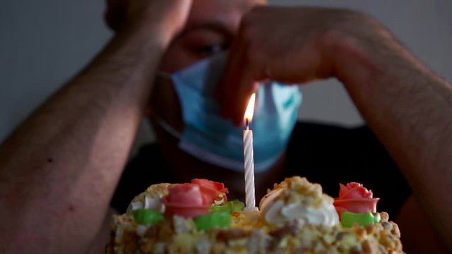 unhappy man is celebrating his birthday alone at self-isolation, cake with one candle