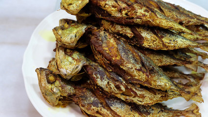 Many fried Shrimp Scad fishes stacked together on a serving plate.