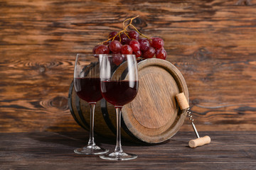 Wooden barrel and glasses of wine on table