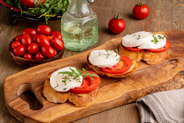 mozzarella with tomato slice on the toast on wooden board