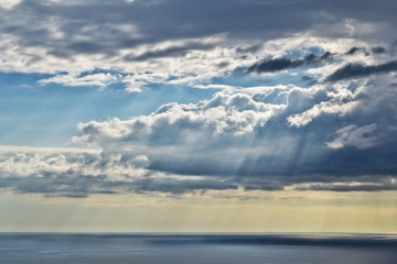 Obraz premium Sun rays and rain from a remote cloud at sea