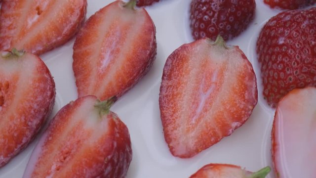 beautiful ripe strawberry in milk close-up,sliced strawberry rotating,fruit macroshooting,healthy food and diet concept,source of vitamins,isolated half strawberry on white background rotates