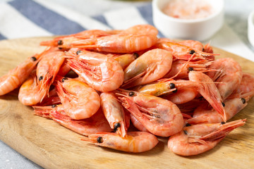 Prawns on a wooden Board on the light gray kitchen table. Lots of prawns on the serving board