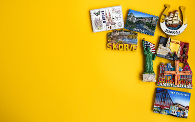 Magnets from different countries on yellow background, travel concept, copy space