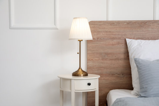 Stylish lamp on table in bedroom
