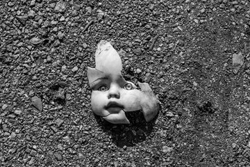 Scary broken doll face on a ground