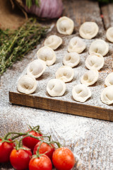 Semi-finished pelmeni dumplings on wooden board