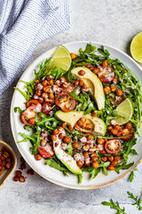 Roasted chickpea salad with avocado and tomatoes in white bowl, top view.  Healthy vegan food concept.