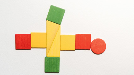 Different colorful shapes wooden on white background. Geometric shapes red, green, yellow colors, top view. Concept of geometry. Copy space. Children educational logical task. Flat lay.