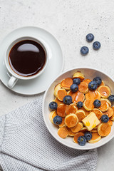 Pancake cereal with butter and berries in a white bowl, top view. Breakfast food concept.