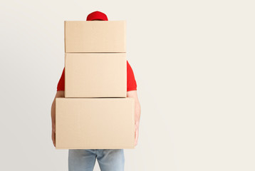 Online shopping and package delivery. Courier holds many large parcels, covering face