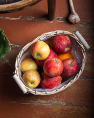 Basket with red and yellow apples standing on the floor