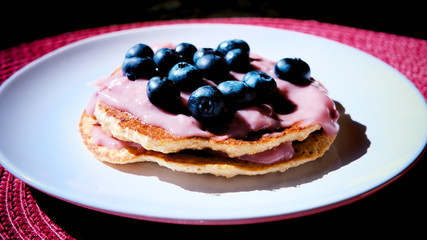 Blueberry pancakes for breakfast. Pancakes with sauce and blueberries on white dishes.