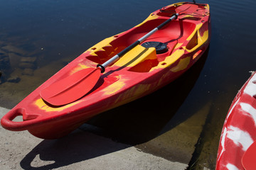 Kayak red and yellow with a paddle on the shore