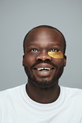 Obraz premium Skin Care. Portrait Of Male Model Applying Yellow Under Eye Patches. Beauty Cosmetic Mask On Face. Face Care Routine. Cosmetology Facial Treatment.