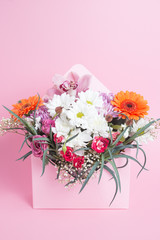 Bouquet of flowers in an original box on a pink background.