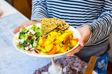 Cooked vegetables - potato, carrot, green salad and tortilla, chapati bread. Balanced vegan food.