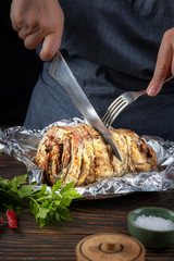 Hands of a cook woman are cutting baked meat, closeup, shallow depth of field, selective focus. Delicious homemade food concept.