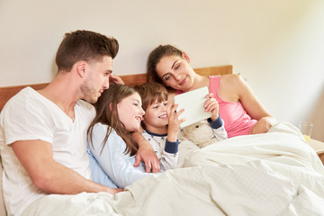 Kinder und Eltern mit Tablet Computer im Bett