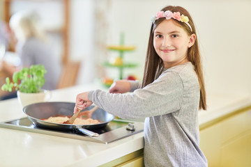 Mädchen mit einer Pfanne am Herd beim kochen