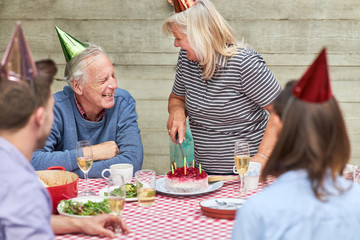 Senioren feiern mit Familie Geburtstag mit Kuchen