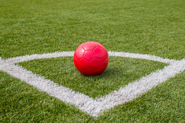 Fototapeta na wymiar a red soccer ball lies in the corner of the soccer field next to the line
