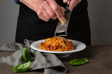 Pasta with bolognese sauce and parmesan. Plate with spaghetti on a stone table