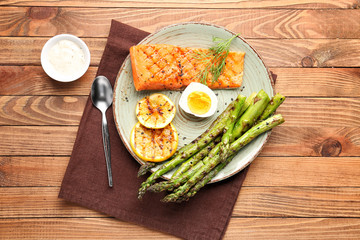 Cooked asparagus with salmon, egg and lemon on table