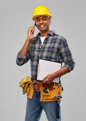 profession, construction and building - happy smiling indian worker or builder in helmet with clipboard calling on smartphone over grey background