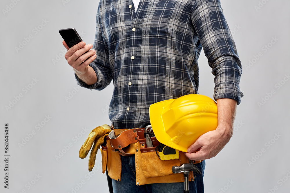 Wall mural repair, construction and building - male worker or builder with smartphone and working tools on belt over grey background