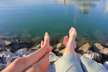 Relaxed couple sitting with feet at beach with blue sea view