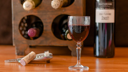 A GLASS OF WINE WITH SEVERAL BOTTLES OF WINE IN THE BACKGROUND 