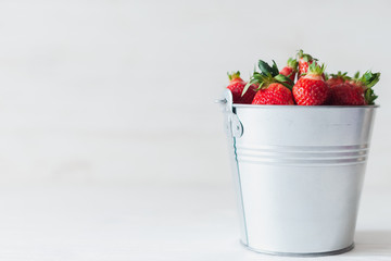 Juicy fresh strawberries in a metal bucket on a white background