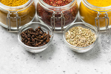 Spices and condiments in glass jars on a light gray table. Spices close-up with space for text