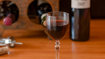 A GLASS OF WINE WITH SEVERAL BOTTLES OF WINE IN THE BACKGROUND 