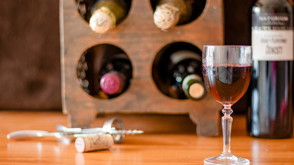 A GLASS OF WINE WITH SEVERAL BOTTLES OF WINE IN THE BACKGROUND 