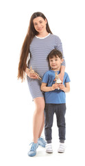 Beautiful pregnant woman with her little son on white background