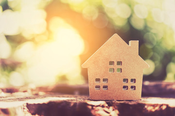 Small home model on wooden table with nature green bokeh abstract background. Family life and...